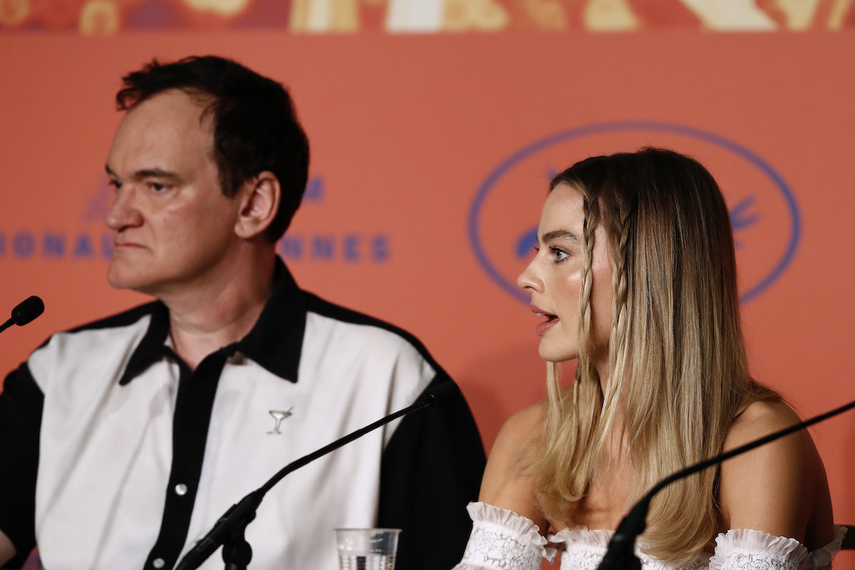 Quentin Tarantino scowls as Margot Robbie talks during a Cannes press conference.