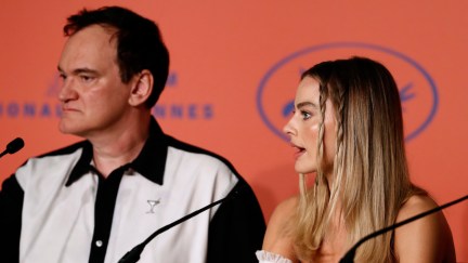 Quentin Tarantino scowls as Margot Robbie talks during a Cannes press conference.