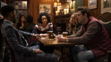 The four main characters of Four Weddings & a Funeral sit around a table in a bar.