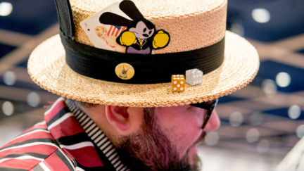 A man wears an old-fashioned straw hat with Disney details for Dapper Day.