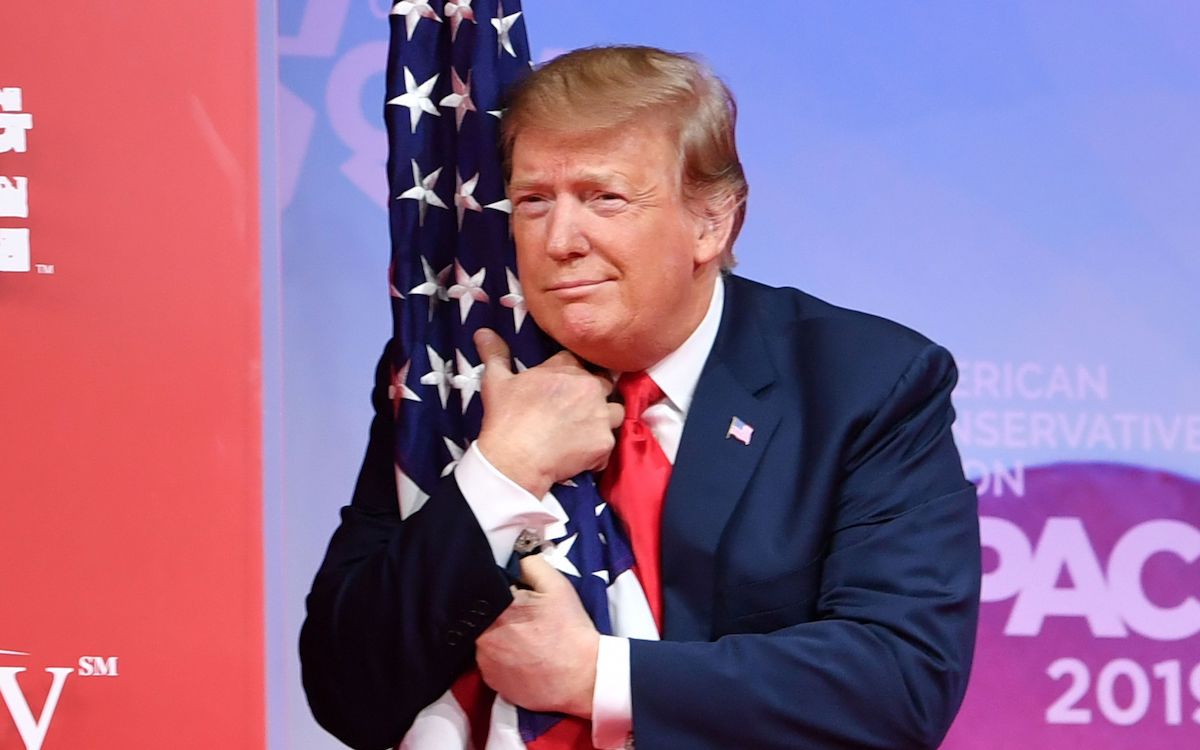 Donald Trump hugs a flag, presumably without its consent.