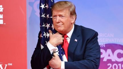 Donald Trump hugs a flag, presumably without its consent.