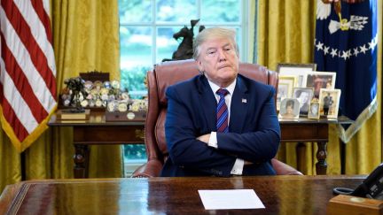 Donald Trump crosses his arms and looks pouty behind his Oval Office desk.