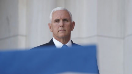 Mike Pence peeks out from behind a flag with an expression that screams 'soon.'