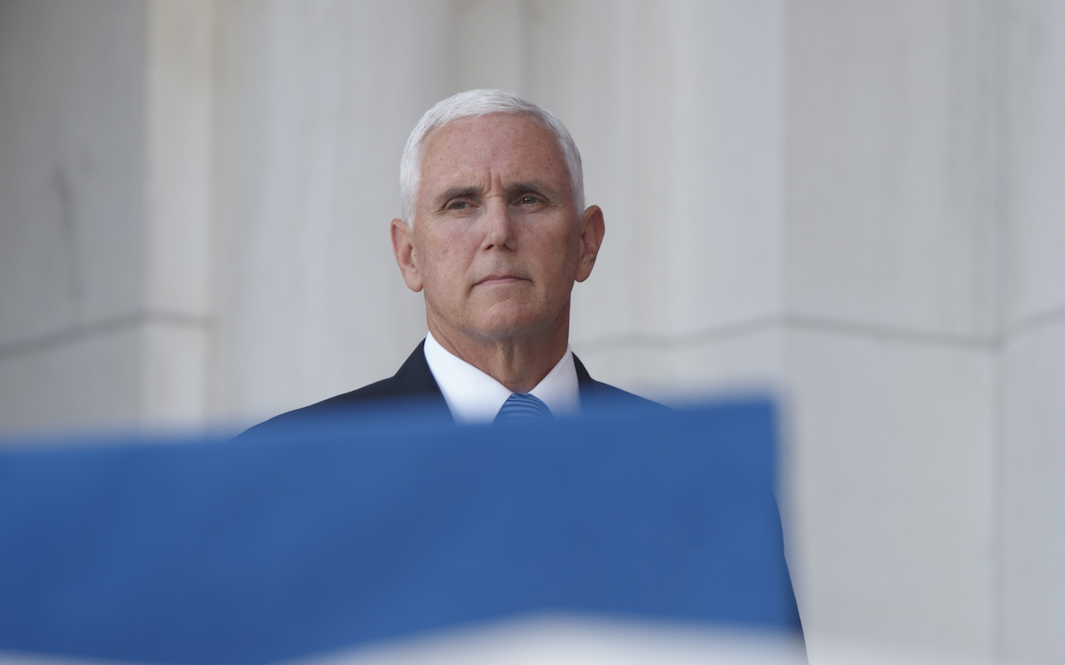 Mike Pence peeks out from behind a flag with an expression that screams 'soon.'