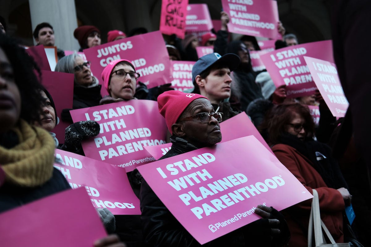 Protestors hold signs reading "I stand with Planned Parenthood"
