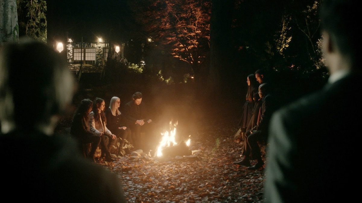 The Magicians characters sit around a campfire together.
