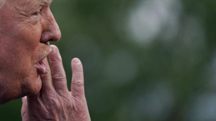 Donald Trump talks secretively behind his hand, probably because he's saying something racist.