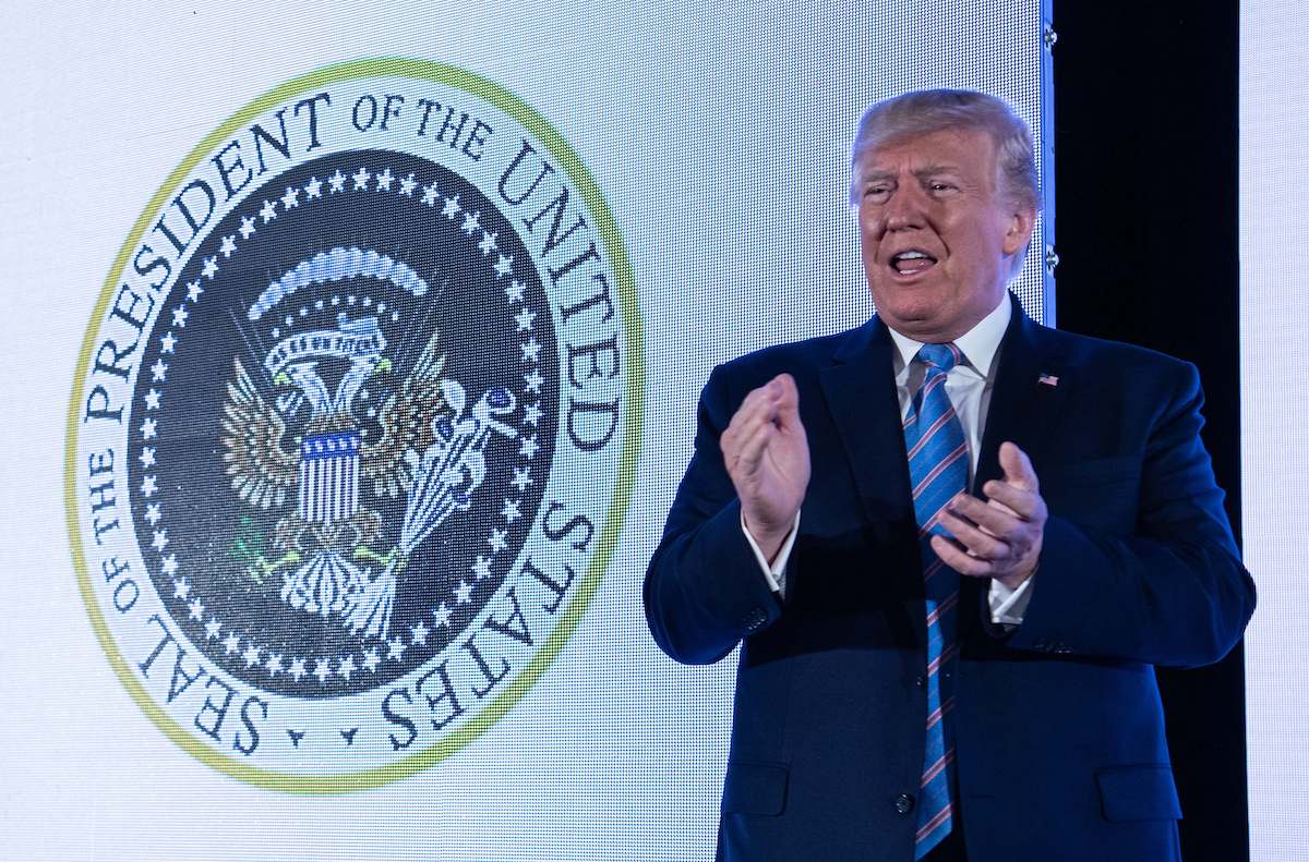 U.S. President Donald Trump stands next to a surreptitiously altered presidential seal as he arrives to address the Turning Point USAs Teen Student Action Summit.