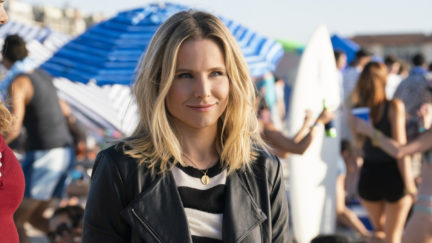 Veronica Mars (Kristen Bell) stands on a crowded beach in a leather jacket.