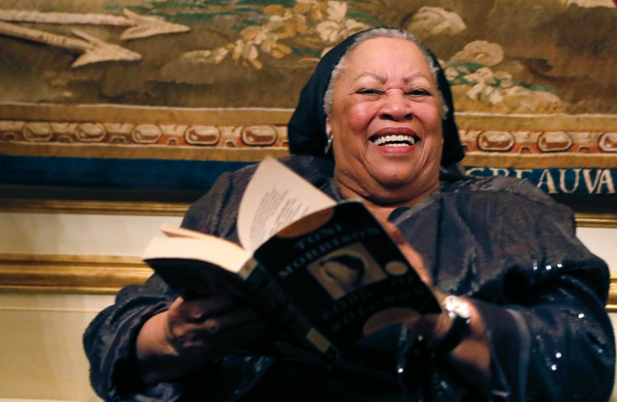 US author Toni Morrison (C) poses with her 1977 novel entitled "Song of Solomon" on September 21, 2012 during a reception sponsored by the US ambassador Charles H. Rivkin (R) at his residence in Paris, as part of the 10th America Festival. The America Festival is a cultural event held in France every two years which gathers well-known figures from the world of literature, music and cinema. AFP PHOTO / PATRICK KOVARIK (Photo credit should read PATRICK KOVARIK/AFP/GettyImages)