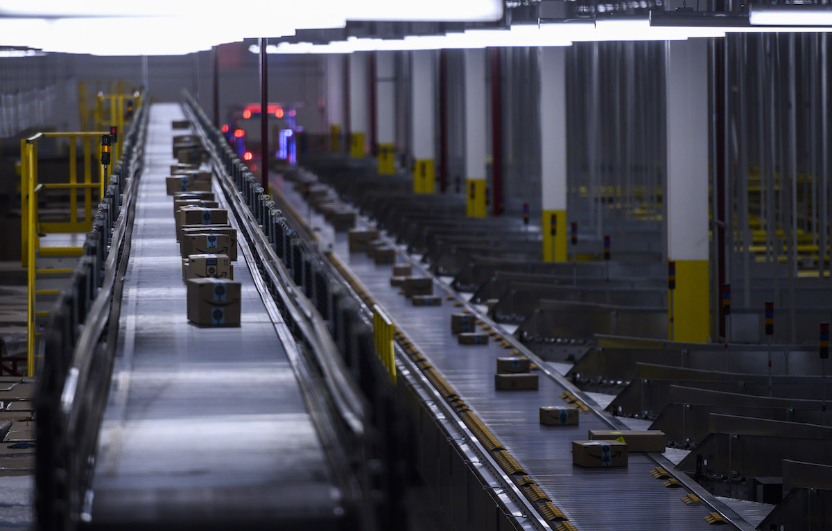 Amazon packages on a conveyor belt in a factory room.