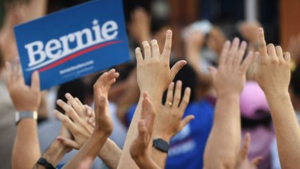 People cheer as 2020 Democratic presidential hopeful Vermont US Senator Bernie Sanders (off frame) arrives to speak to a crowd of supporters during a campaign rally