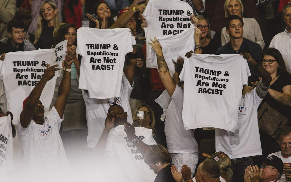 Trump supporters hold shirts at a rally that read "Trump and Republicans are not racist."