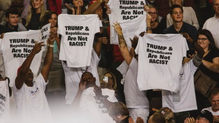 Trump supporters hold shirts at a rally that read 