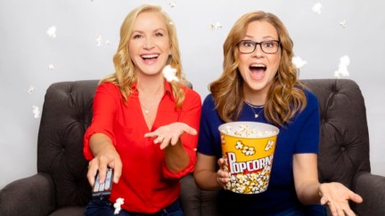 Angela Kinsey and Jenna Fischer sit together on a couch, holding popcorn.