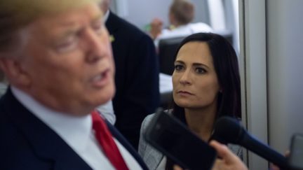 White House Press Secretary Stephanie Grisham listens as US President Donald Trump speaks to the media.