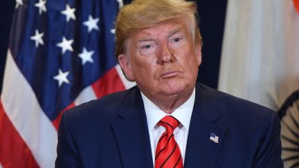 Donald Trump sits in front of an American flag looking sweaty at the UN.