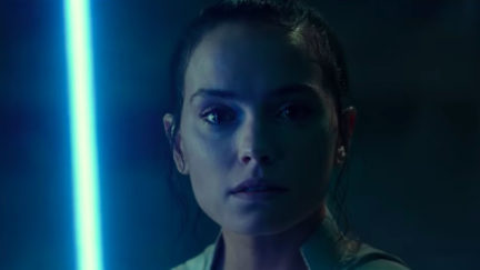 Rey stares into the camera, holding up a blue lightsaber in Star Wars: The Rise of Skywalker trailer.
