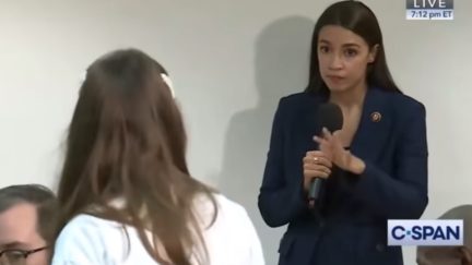 AOC listens patiently to a constituent at a town hall event.