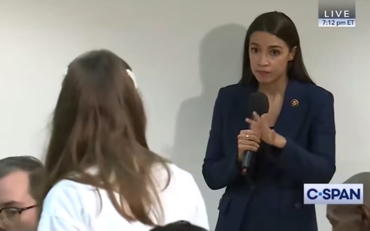 AOC listens patiently to a constituent at a town hall event.
