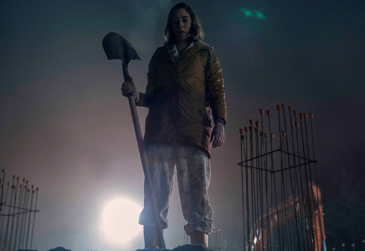 Annie Wilkes stands with a shovel looking into the pit