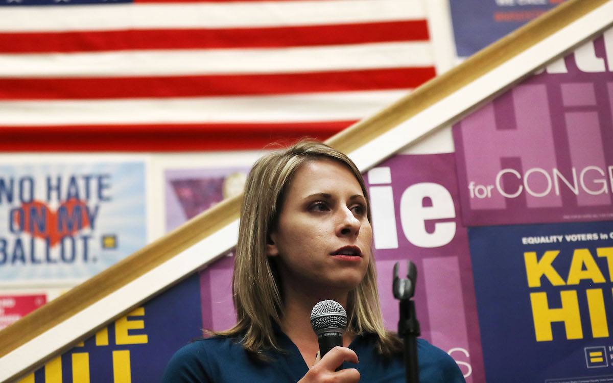 Katie Hill speaks to supporters in front of a number of progressive signs.