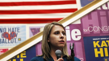 Katie Hill speaks to supporters in front of a number of progressive signs.