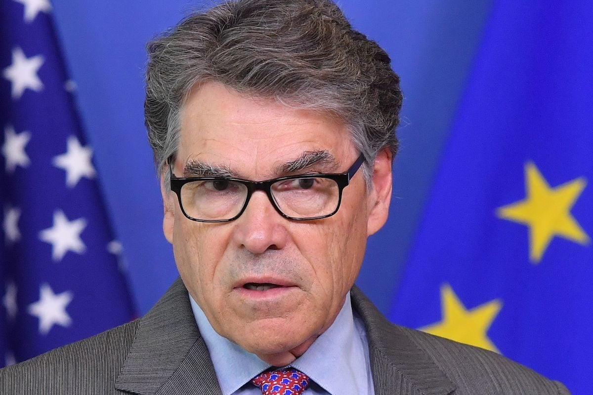 Rick Perry stands in front of flags looking confused.