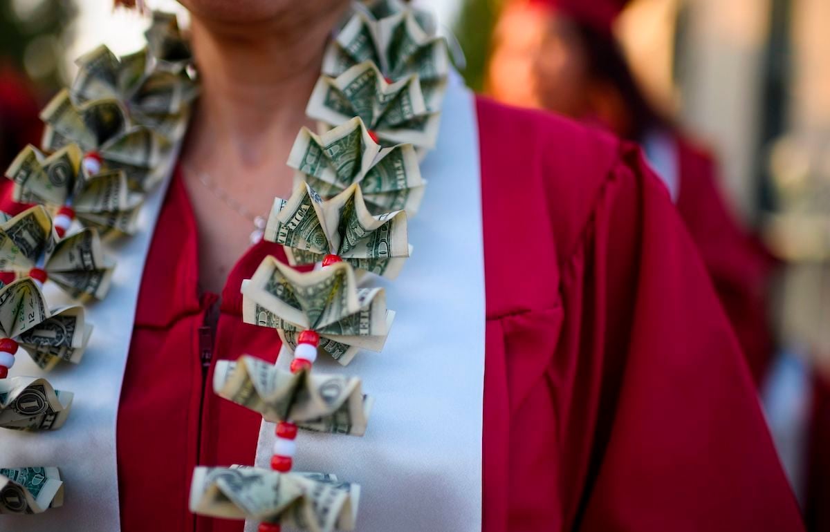 A graduating student wears a money lei, a necklace made of US dollar bills.