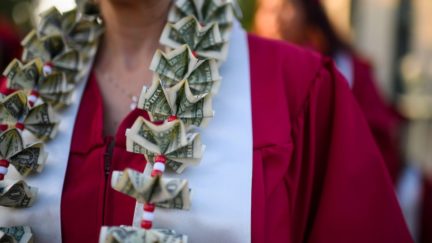 A graduating student wears a money lei, a necklace made of US dollar bills.