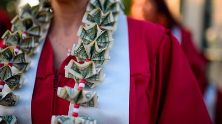 A graduating student wears a money lei, a necklace made of US dollar bills.