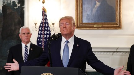Trump makes Jesus arms as Mike Pence looks on in front of George Washington's portrait.