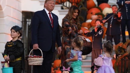 Donald Trump smiles awkwardly around children in Halloween costumes outside the White House.