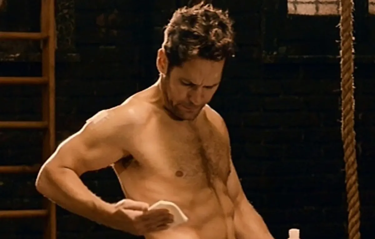 Paul Rudd standing shirtless putting on some kind of medicine