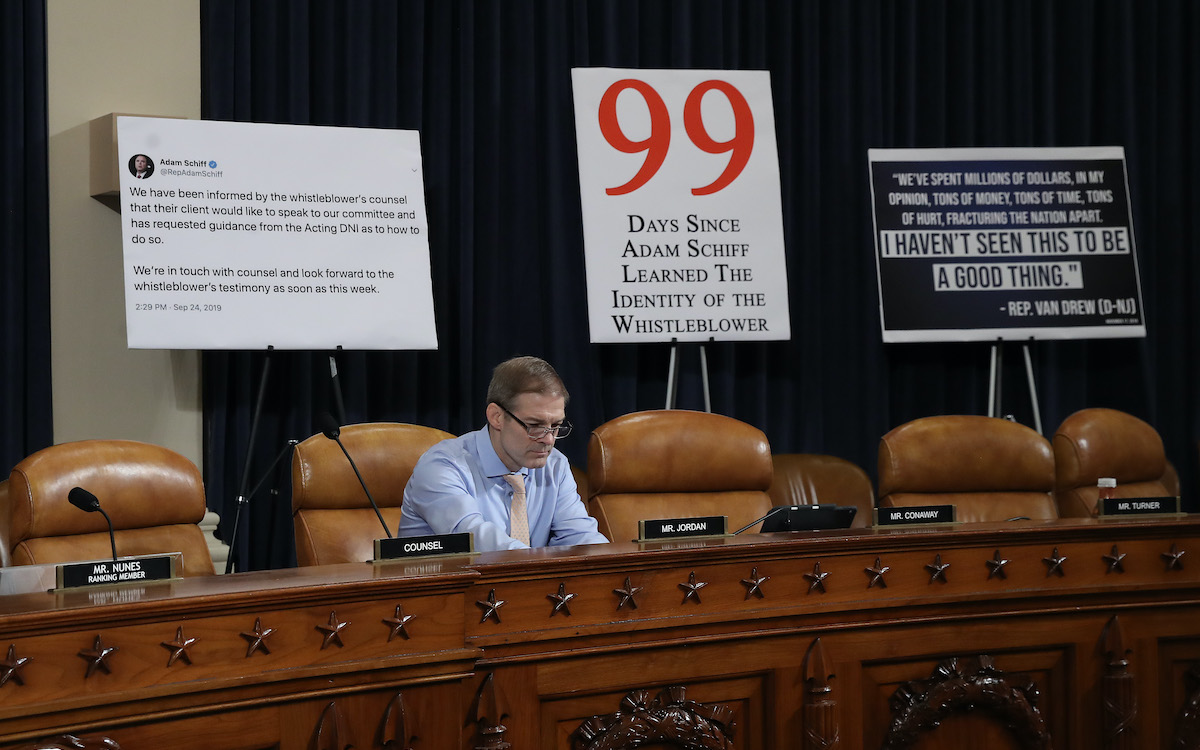 Rep. Jim Jordan sits alone in a Capitol Hill hearing room in front of a bunch of stupid giant signs.