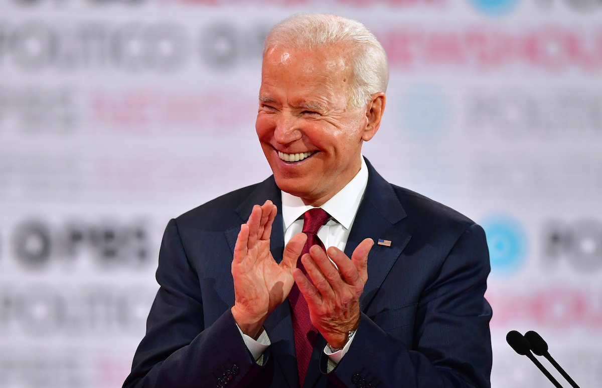 Joe Biden laughs and claps on the debate stage.