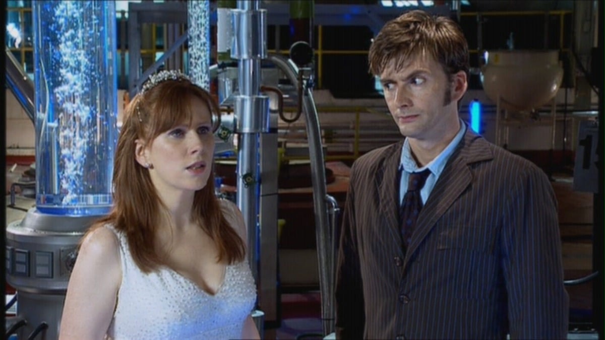 Donna Noble in a wedding dress as the Doctor raises an eyebrow at her.