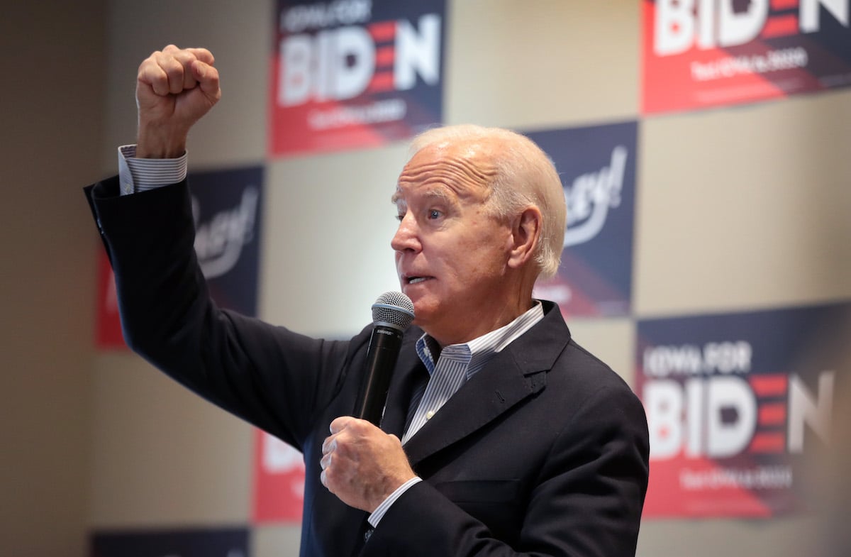 Joe Biden holds a microphone and raises a fist at an Iowa event.