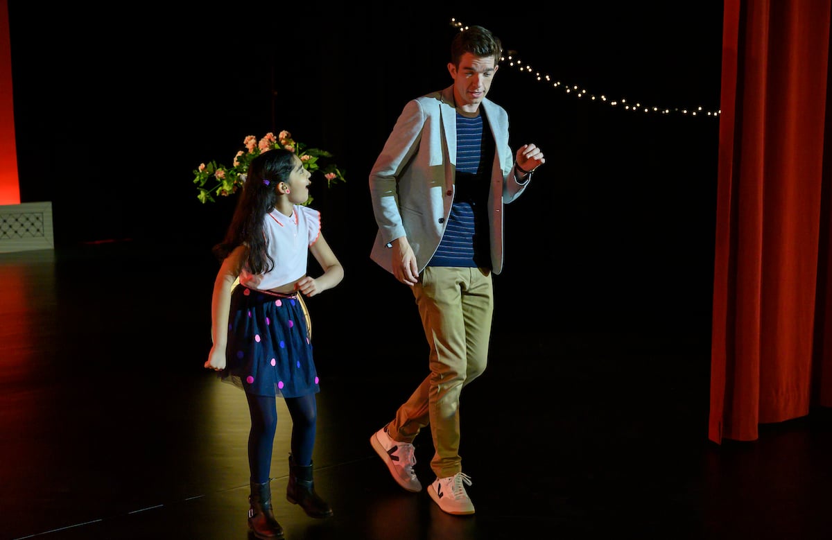 John Mulaney and a young girl dance on a stage.