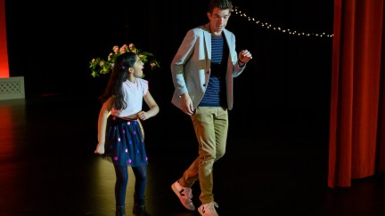 John Mulaney and a young girl dance on a stage.