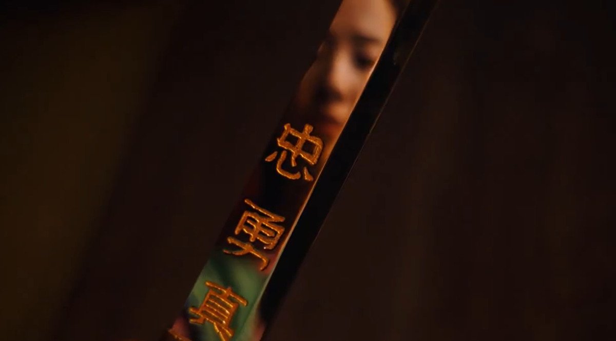Mulan looking at herself in the reflection of her sword