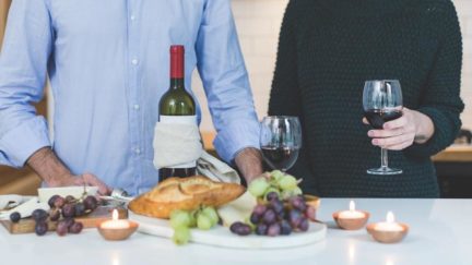 Heterosexual couple with wine and a cheese plate in front of them.
