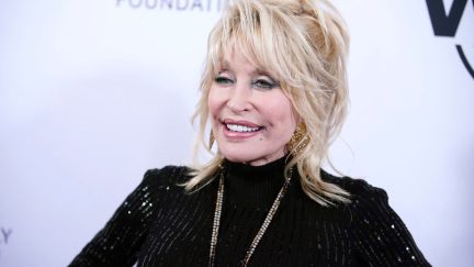 dolly parton grins on a red carpet
