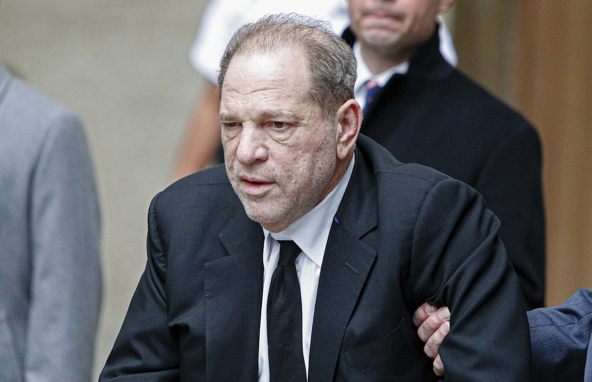 Harvey Weinstein leaves court as someone holds his arm.