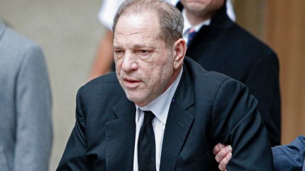 Harvey Weinstein leaves court as someone holds his arm.