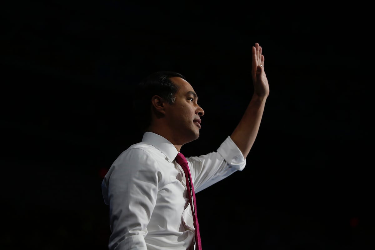 Julian Castro waves in profile in front of a black background.