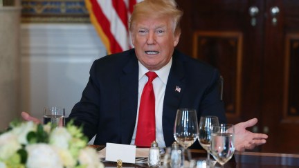 Donald Trump gestures at a dinner table.