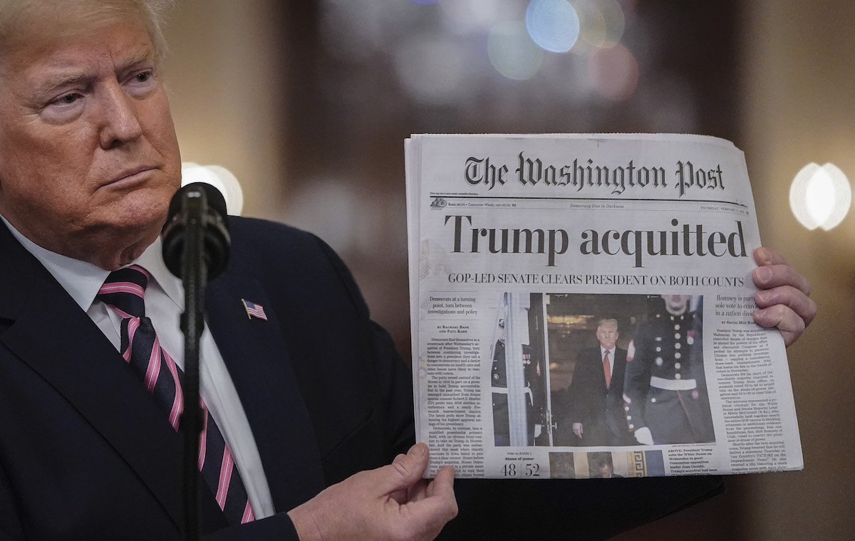 Donald Trump holds a copy of The Washington Post as he speaks in the East Room of the White House one day after the U.S. Senate acquitted on two articles of impeachment
