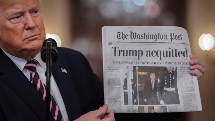 Donald Trump holds a copy of The Washington Post as he speaks in the East Room of the White House one day after the U.S. Senate acquitted on two articles of impeachment